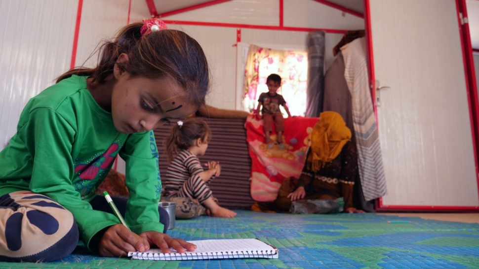 A Syrian little girl doing her homework in emergency-built homes